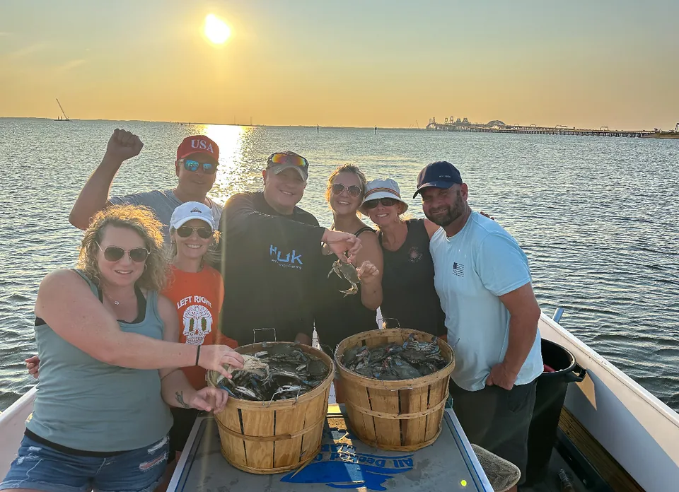 Crabbing charter group with two baskets of blue crabs at sunset on the Chesapeake Bay